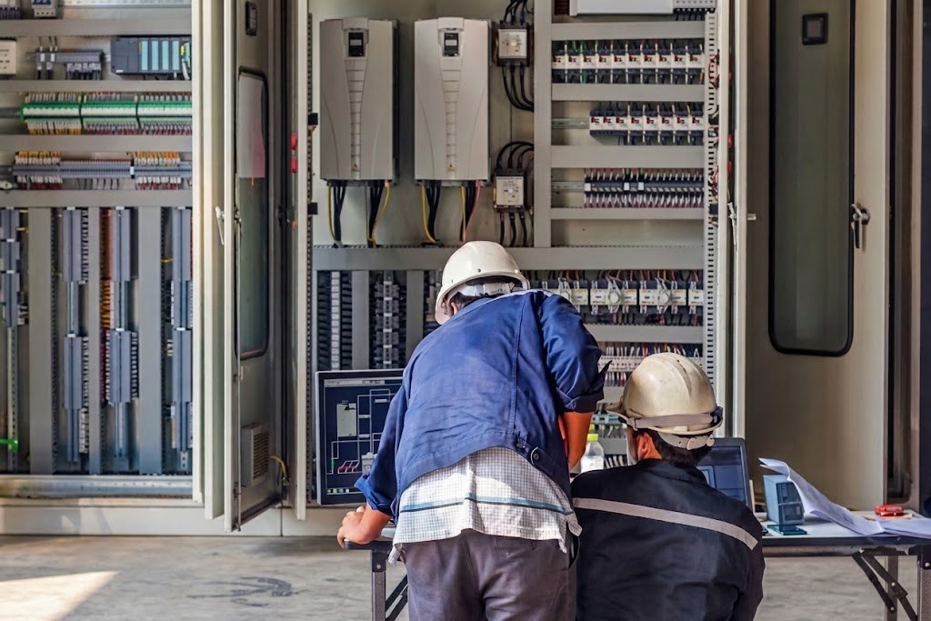 Técnicos con casco revisando un tablero eléctrico de control